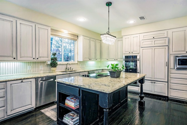 kitchen with pendant lighting, sink, a center island, built in appliances, and light stone countertops