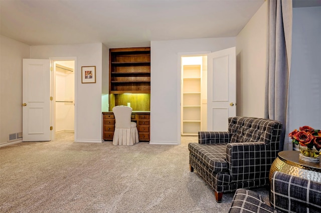 sitting room with built in shelves and carpet floors