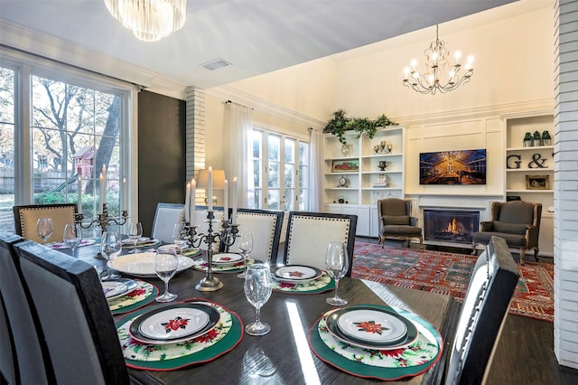 dining space with built in shelves, dark hardwood / wood-style flooring, crown molding, and a notable chandelier