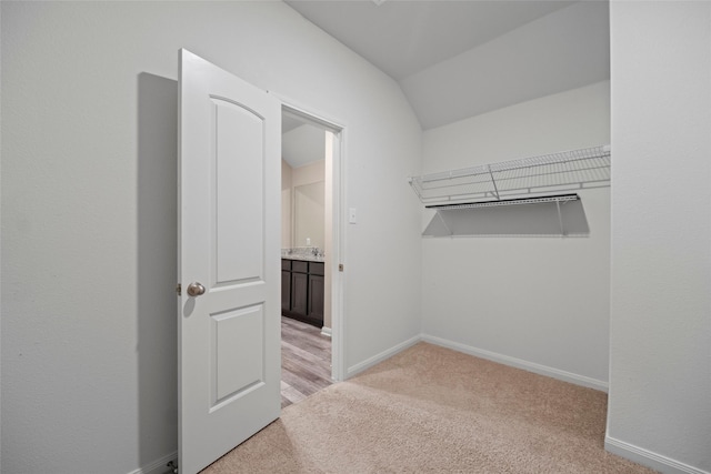 walk in closet featuring light colored carpet and lofted ceiling