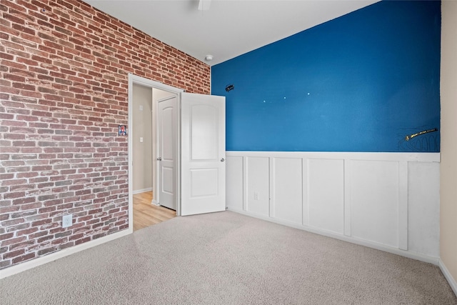 carpeted empty room with brick wall