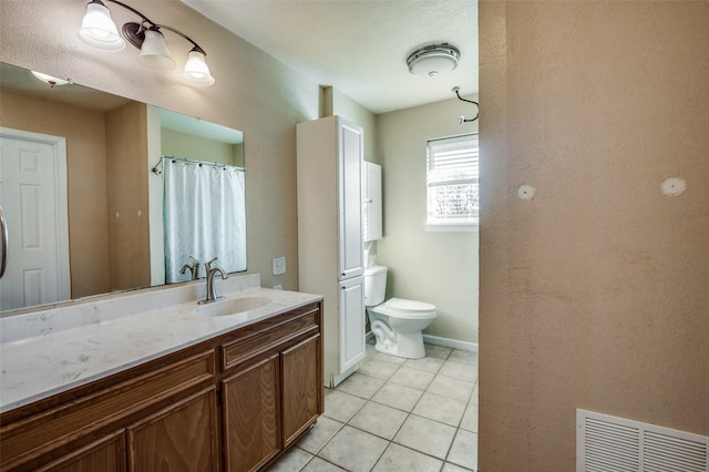 bathroom with toilet, vanity, and tile patterned floors