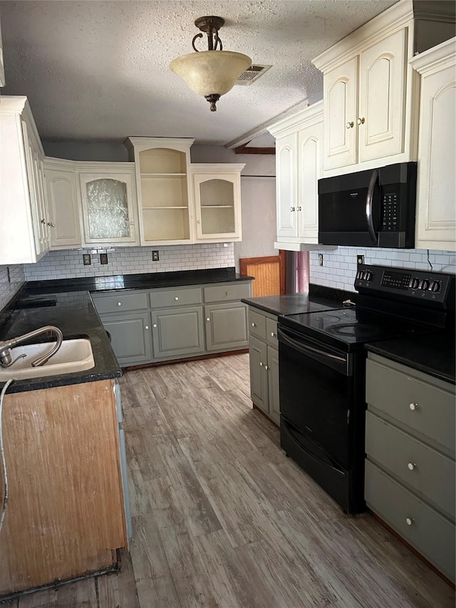 kitchen with a textured ceiling, gray cabinets, black range with electric stovetop, and light hardwood / wood-style flooring