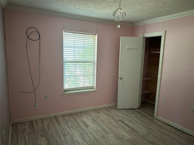 unfurnished bedroom with an inviting chandelier, a textured ceiling, a closet, and light hardwood / wood-style flooring