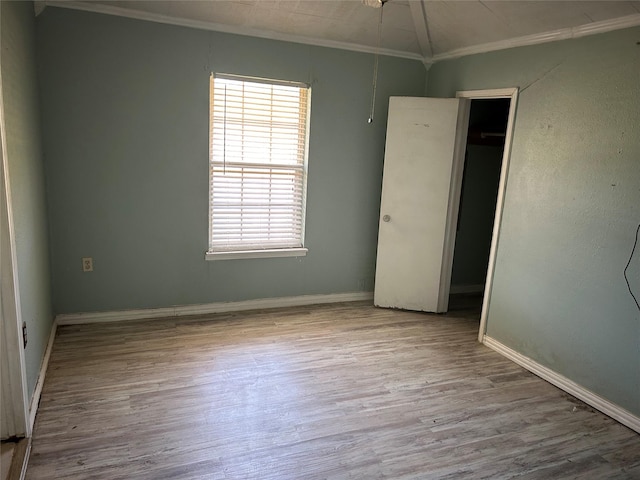 unfurnished bedroom featuring multiple windows, a closet, light wood-type flooring, and ornamental molding