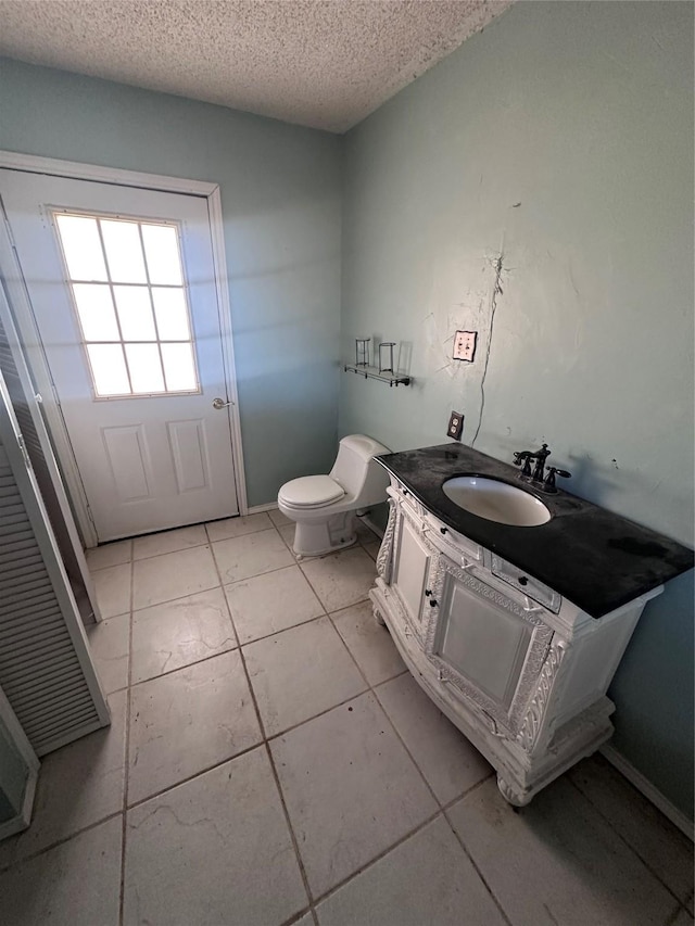 bathroom featuring tile patterned flooring, vanity, a textured ceiling, and toilet