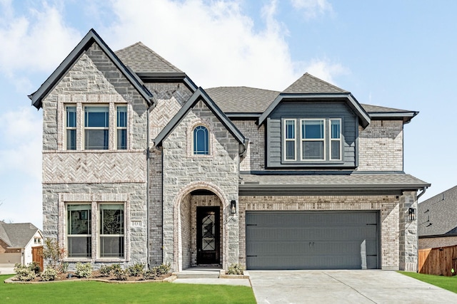 french country home with a shingled roof, concrete driveway, stone siding, an attached garage, and brick siding