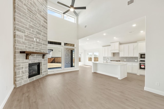 interior space with ceiling fan, a fireplace, visible vents, and light wood-style floors