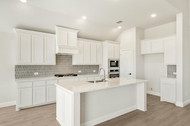 kitchen with stainless steel appliances, white cabinets, a sink, and tasteful backsplash