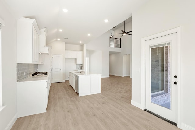 kitchen with tasteful backsplash, appliances with stainless steel finishes, light wood-type flooring, white cabinetry, and a sink