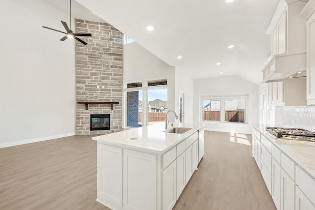 kitchen with open floor plan, a sink, a stone fireplace, and stainless steel gas cooktop