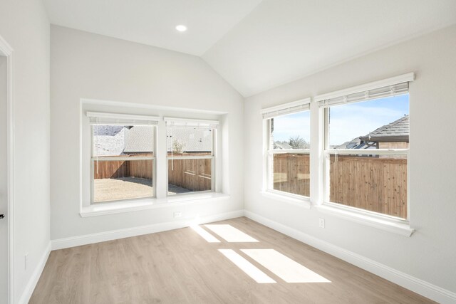 unfurnished room with lofted ceiling, baseboards, and wood finished floors