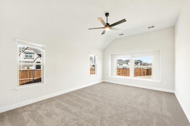 carpeted spare room with a healthy amount of sunlight, visible vents, and vaulted ceiling