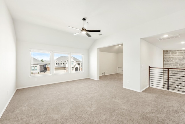 empty room with lofted ceiling, carpet floors, visible vents, and a ceiling fan