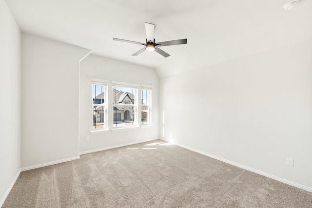 carpeted spare room featuring vaulted ceiling, ceiling fan, and baseboards