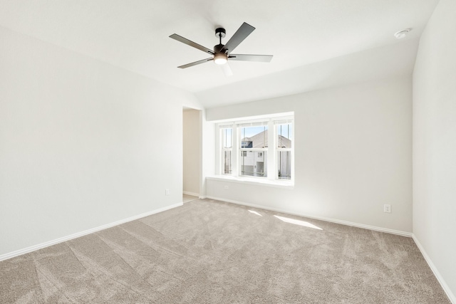 spare room featuring carpet floors, lofted ceiling, baseboards, and a ceiling fan