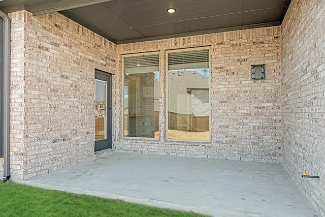 doorway to property with a patio area and brick siding