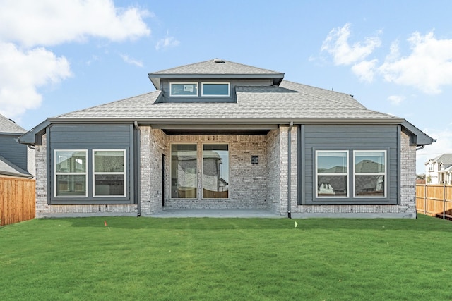 rear view of property with a patio, a shingled roof, a lawn, and fence