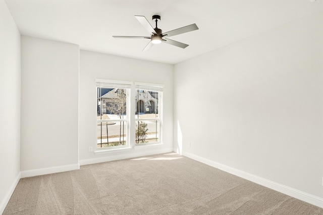 carpeted spare room featuring ceiling fan and baseboards