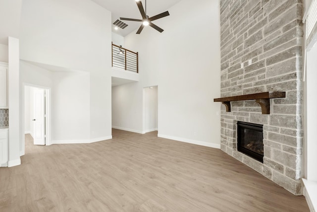 unfurnished living room featuring a fireplace, wood finished floors, visible vents, baseboards, and a ceiling fan