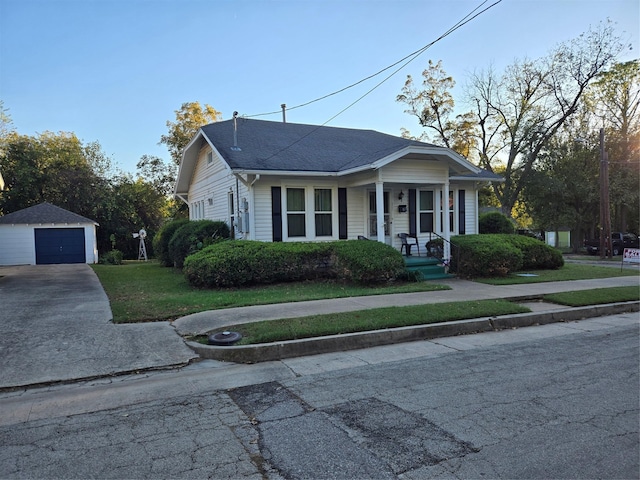 bungalow-style house with a garage, an outbuilding, and a front lawn