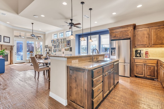 kitchen with sink, crown molding, decorative light fixtures, appliances with stainless steel finishes, and a kitchen island with sink