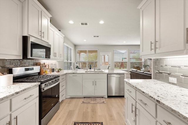 kitchen with white cabinets, backsplash, sink, and stainless steel appliances