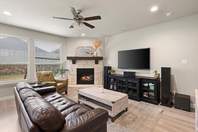 living room with a fireplace, ceiling fan, plenty of natural light, and light wood-type flooring