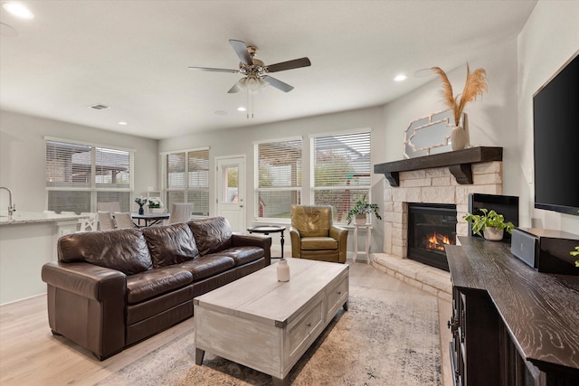 living room featuring ceiling fan, a fireplace, and light hardwood / wood-style floors