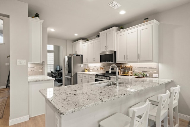 1504 Longspur Dr, Argyle, TX 76226 - kitchen featuring appliances with stainless steel finishes, a sink, decorative backsplash, light stone counters, and light wood-type flooring