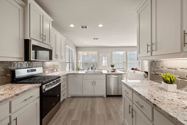 1504 Longspur Dr, Argyle, TX 76226 - kitchen with stainless steel appliances, light wood-style flooring, tasteful backsplash, a peninsula, and recessed lighting
