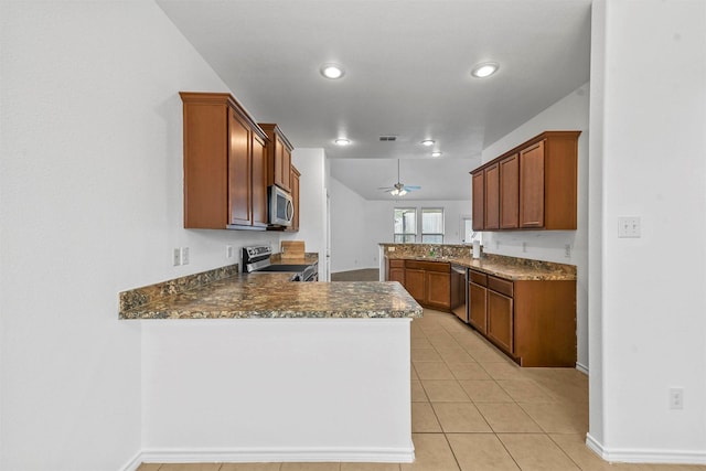 kitchen with kitchen peninsula, appliances with stainless steel finishes, dark stone counters, ceiling fan, and light tile patterned flooring