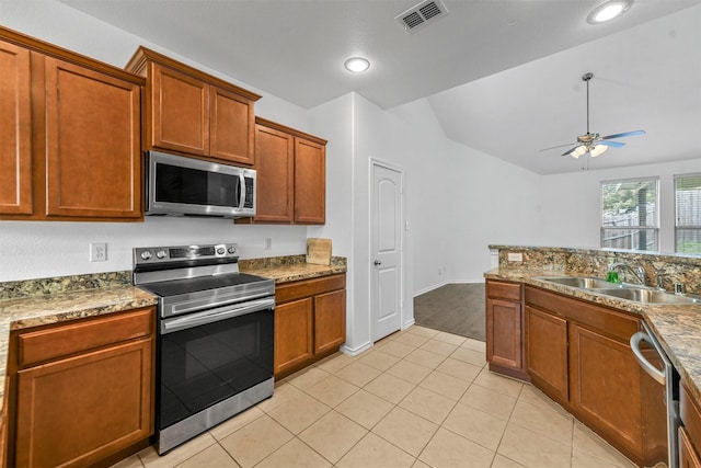 kitchen featuring ceiling fan, sink, stainless steel appliances, light stone counters, and light tile patterned floors