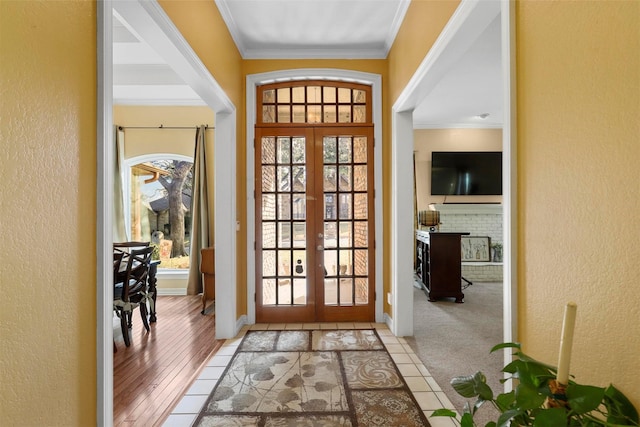 entryway featuring a healthy amount of sunlight, french doors, crown molding, and a fireplace