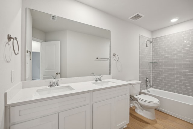 full bathroom featuring vanity, toilet, tiled shower / bath combo, and hardwood / wood-style floors