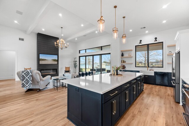 kitchen with high end fridge, a fireplace, dishwasher, a kitchen island, and beam ceiling