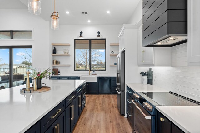 kitchen with pendant lighting, white cabinets, custom exhaust hood, black dishwasher, and electric stove