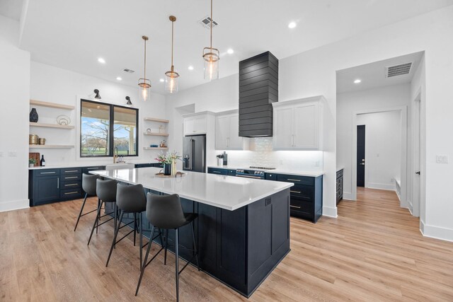 kitchen featuring a spacious island, white cabinets, hanging light fixtures, high end refrigerator, and blue cabinets