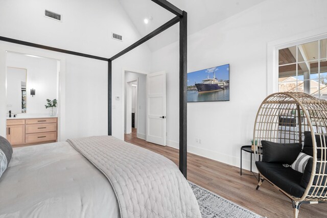 bedroom featuring light hardwood / wood-style floors, connected bathroom, and high vaulted ceiling