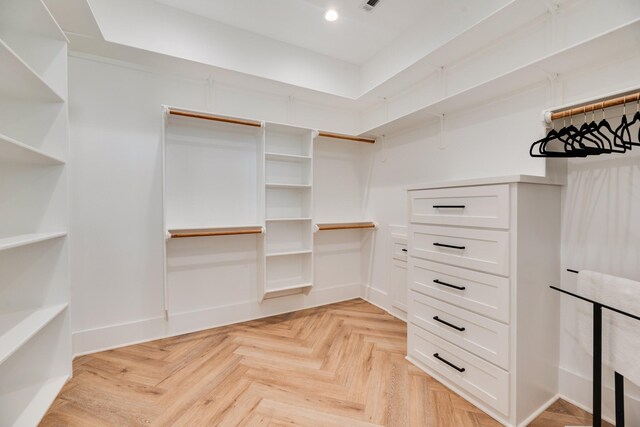 walk in closet with light parquet floors