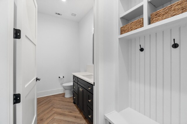 bathroom featuring toilet, vanity, and parquet flooring