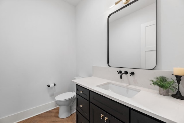 bathroom featuring toilet, vanity, and parquet flooring