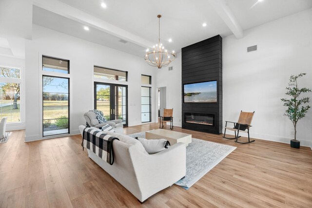 living room with light hardwood / wood-style floors, a high ceiling, a large fireplace, and beamed ceiling