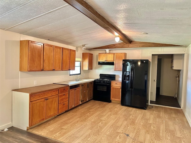 kitchen featuring light wood-type flooring, vaulted ceiling with beams, sink, and black appliances