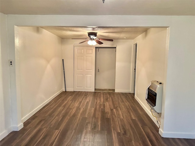 unfurnished living room featuring heating unit, ceiling fan, and dark wood-type flooring