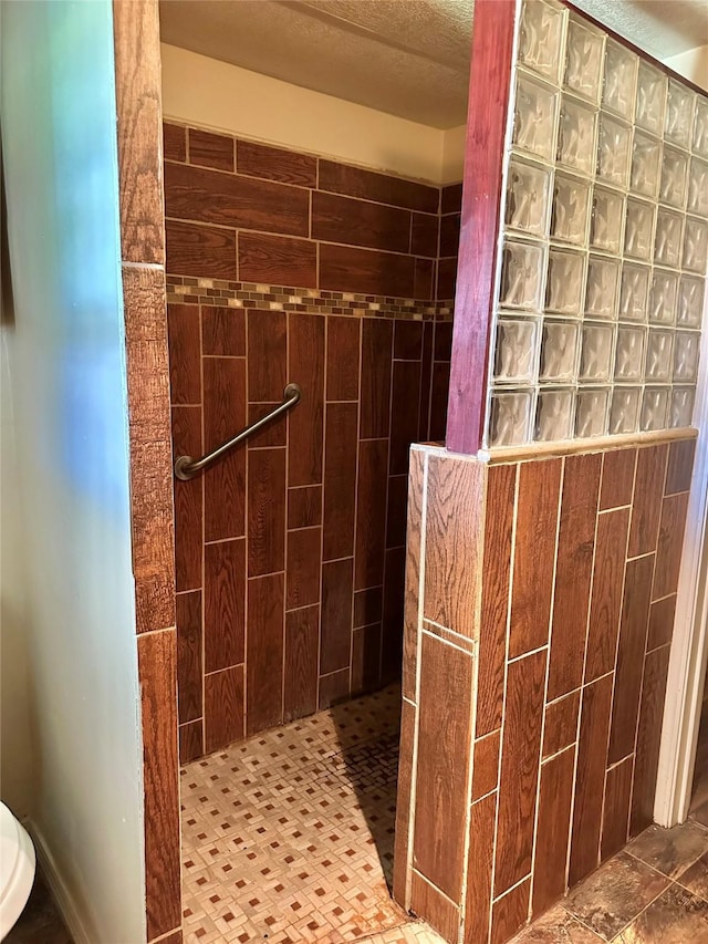 bathroom featuring a tile shower and a textured ceiling