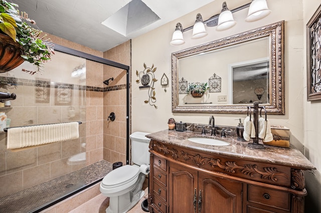 bathroom with toilet, a shower with shower door, vanity, and a skylight