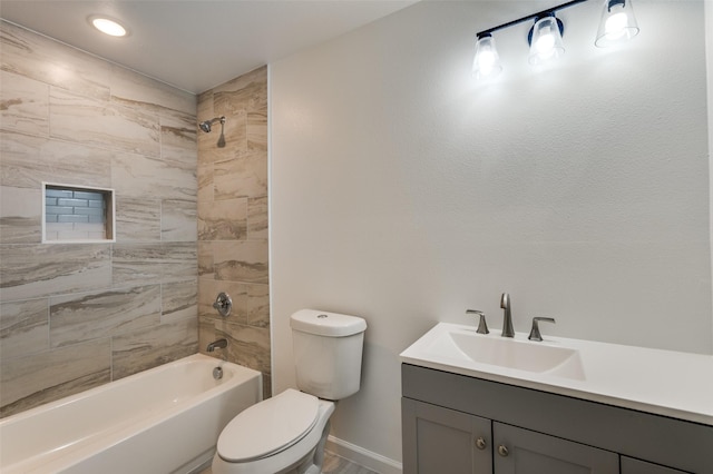 full bathroom featuring tiled shower / bath, vanity, and toilet