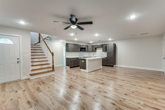 kitchen featuring light hardwood / wood-style flooring, a center island with sink, ceiling fan, dark brown cabinets, and sink