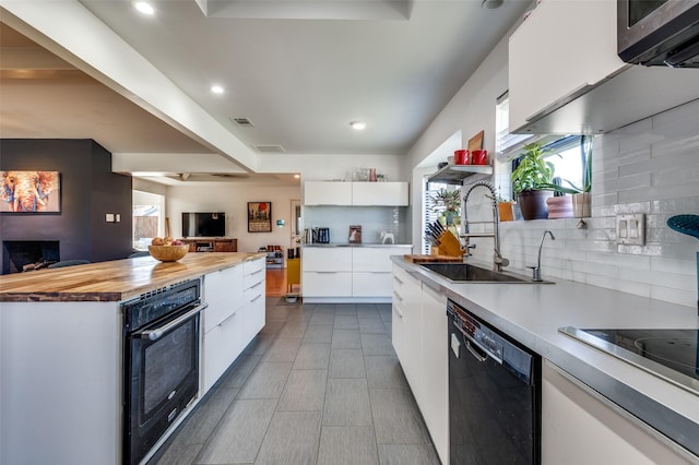 kitchen featuring black appliances, sink, tasteful backsplash, butcher block countertops, and white cabinetry